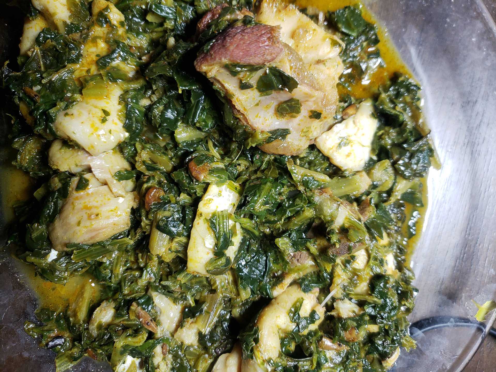 A dish of spinach and chunks of fish in a bowl.