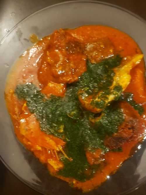 Plate of chicken curry with a side of spinach sauce.