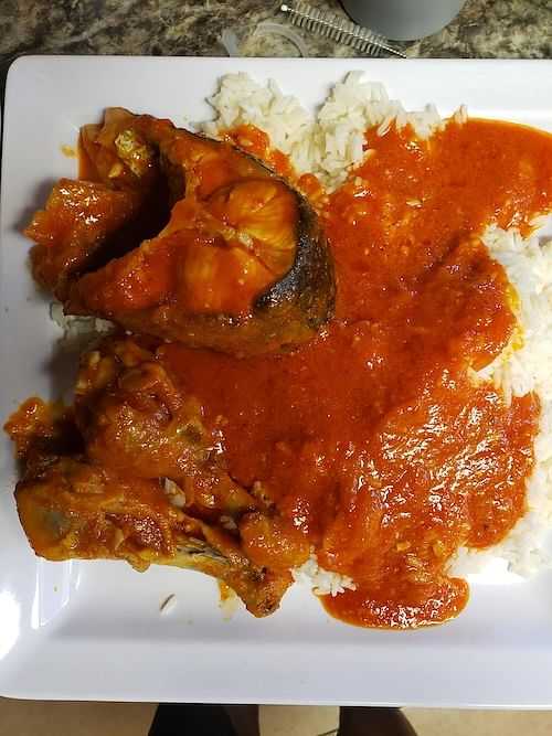 Plate of rice with fish in red sauce.
